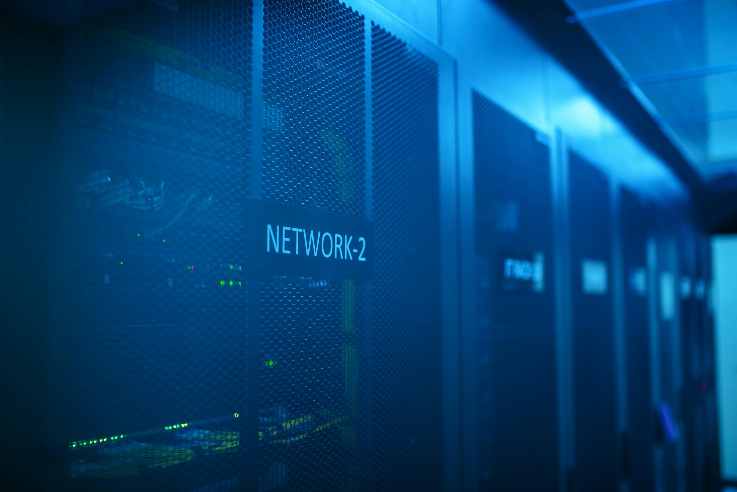 Data center server racks with blue lighting — the physical infrastructure underpinning audit logging and security compliance